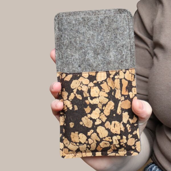 Handytasche aus grauem Filz und Kork mit Kaffee, Fleckenmuster, in einer Hand gehalten