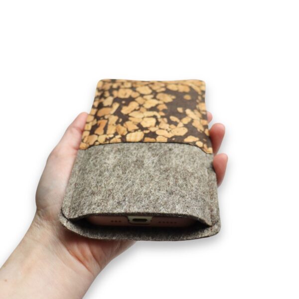 Handytasche aus grauem Filz und Kork mit Kaffee, Fleckenmuster, Ansicht von oben, in einer Hand gehalten