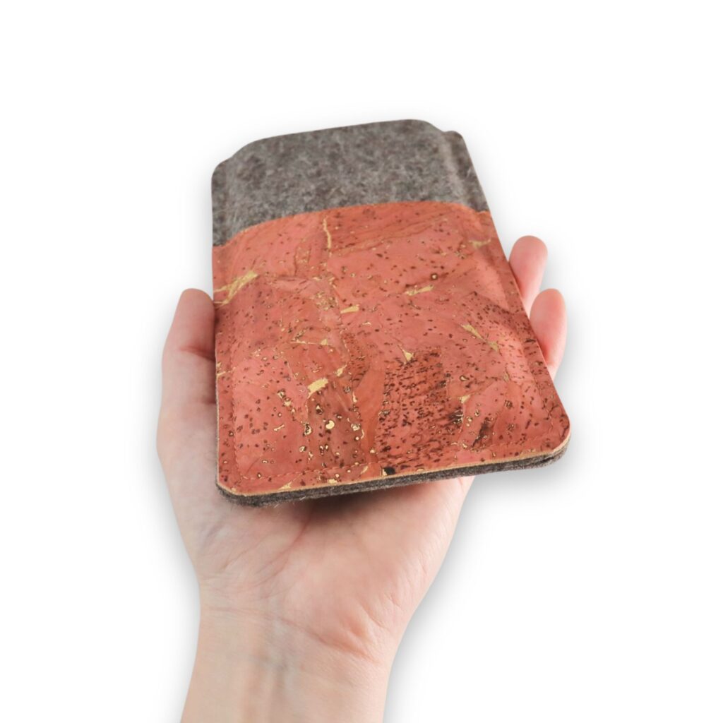 Handgemachte Handytasche aus Filz und korallfarbenem Kork mit Goldmuster, Ansicht von unten, in einer Hand gehalten