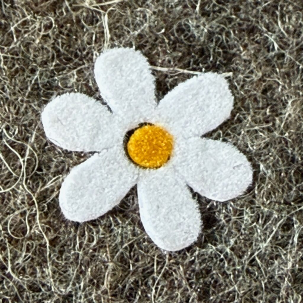 Detailansicht eines Gänseblümchen-Flockprints auf einer Handytasche aus Filz