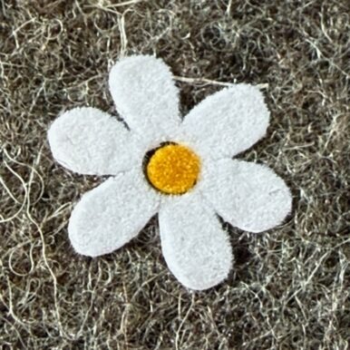 Detailansicht eines Gänseblümchen-Flockprints auf einer Handytasche aus Filz