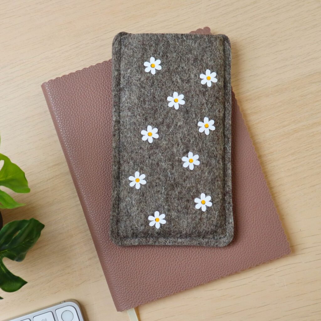 Handytasche aus Wollfilz mit Blumen-Allover-Print, auf einem Schreibtisch liegend