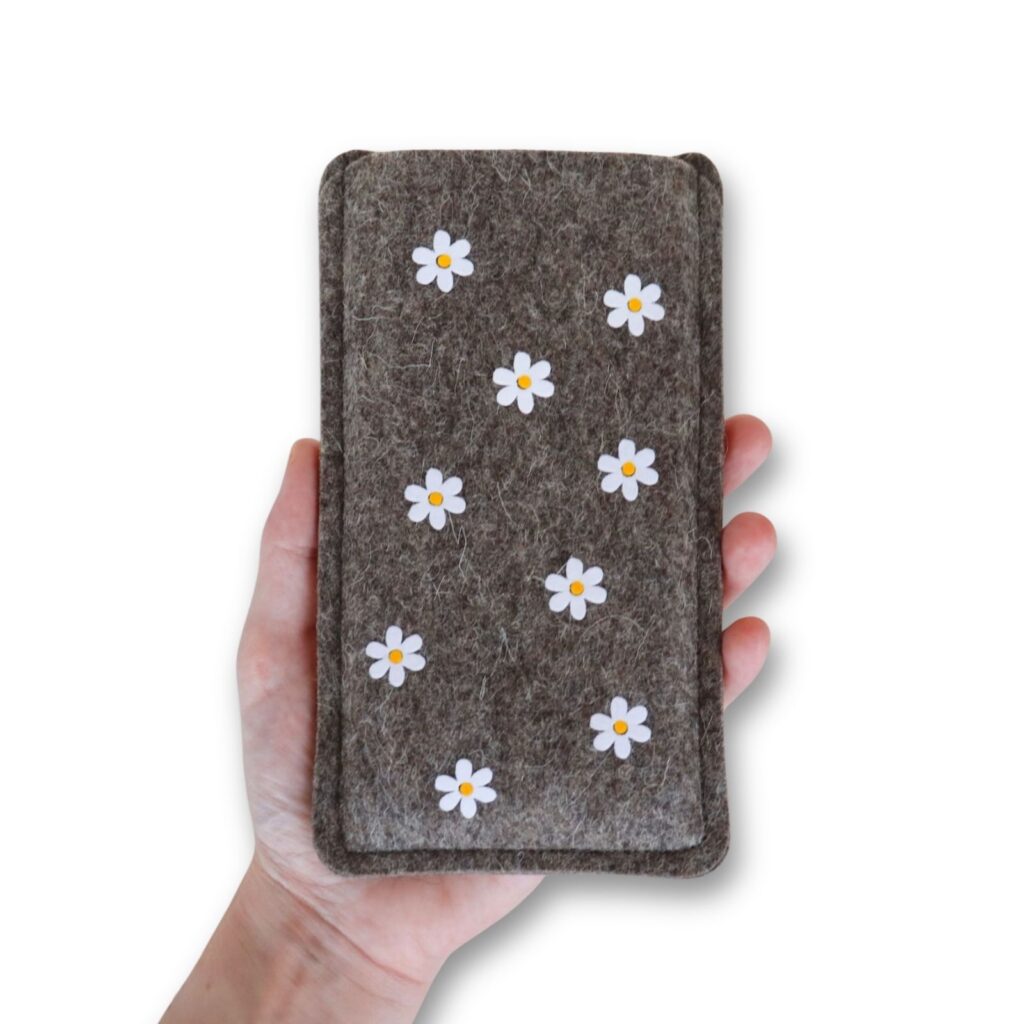 Handyhülle aus Filz mit Gänseblümchen, in einer Hand gehalten