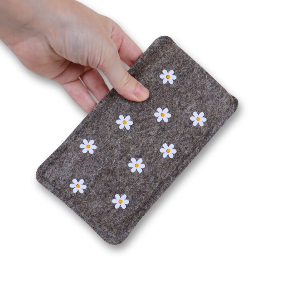 Handytasche aus Filz mit Gänseblümchen, in einer Hand gehalten