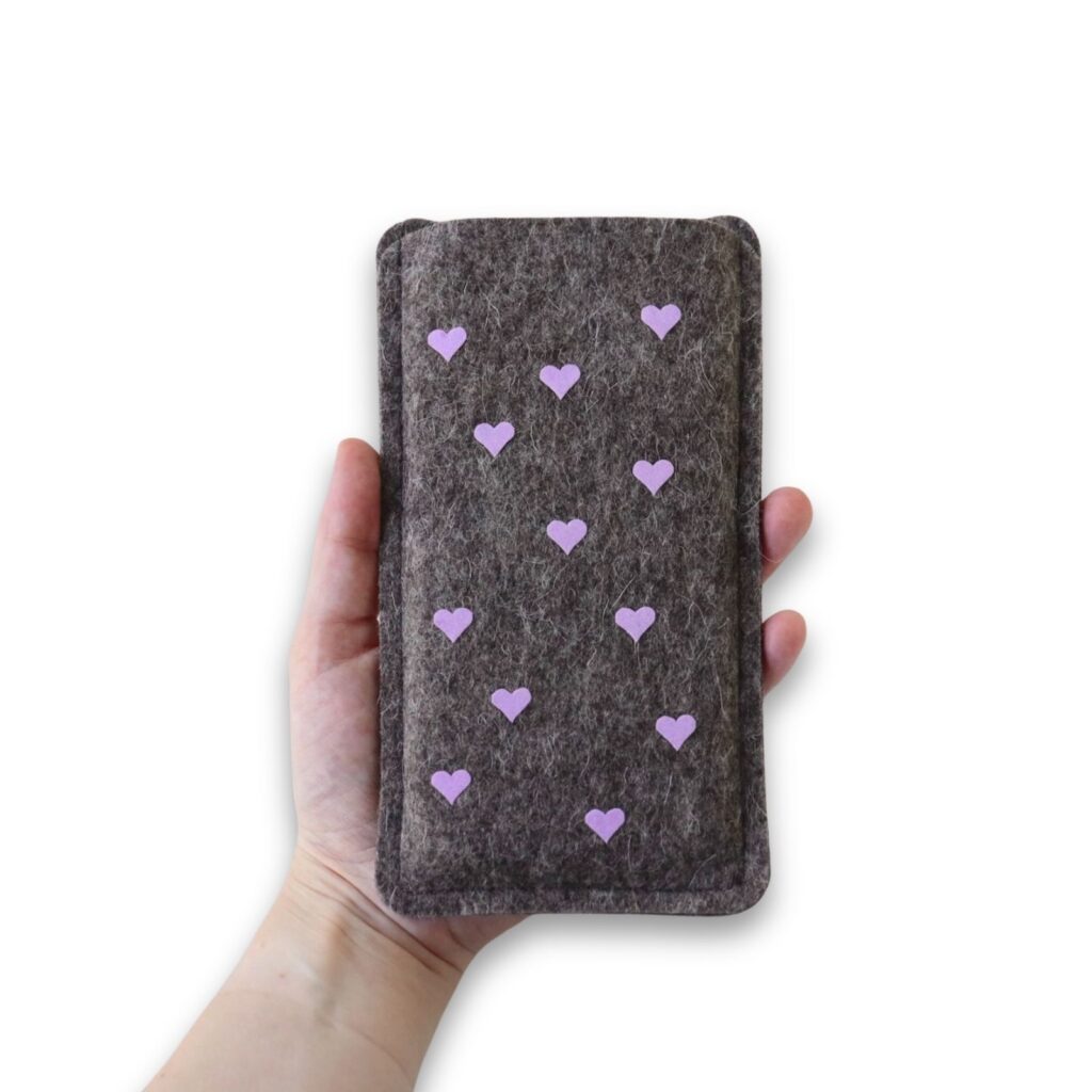 Handytasche aus grauem Filz mit fliederfarbenem Herzen-Allover Print, in einer Hand gehalten