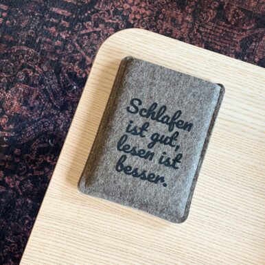 Graue Filzhülle für PocketBook Verse, mit schwarzem Flockprint "Schlafen ist gut, lesen ist besser."