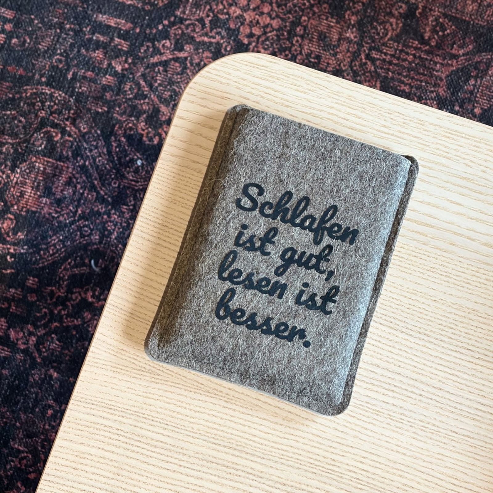 Graue Filzhülle für PocketBook Verse, mit schwarzem Flockprint "Schlafen ist gut, lesen ist besser."